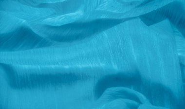 Bulanık, yumuşak, dalgalı kıvrımlı kıvrımları olan, ışığı ve gölgeyi büyüleyici bir şekilde yakalayan lüks mavi bir kumaş. Zengin dokusu derinlik katıyor