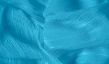 Yumuşak mavi kumaştan oluşan bulanık, dalgalı çizgiler rahatlatıcı bir akış yaratıyor. Kumaştaki pürüzsüz kıvrımlar akışkanlığını artırıyor, dinginlik ve doğal hareket hissi veriyor..