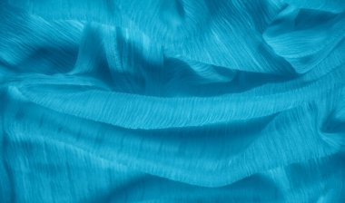 Yumuşak su kumaşının bulanık kıvrımları, ince gölgelerle aydınlatılıyor. Yumuşak doku ve ışık etkileşimi rahatlatıcı ve sakin bir görsel deneyim sunar