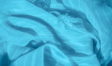Canlı mavi kumaş kıvrımları ve dokuların bulanıklığı rahatlatıcı ve huzurlu bir görüntü yaratır. Akan çizgiler ve yumuşak dalgalar tekstil için bir hareket ve zarafet hissi sunar..