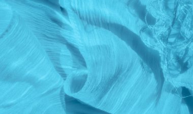 Açık mavi desenli bulanık kumaş zarif bir şekilde yumuşak kıvrımlarla örtülmüş, dingin ve dalgalı bir desen yaratıyor. Nazik çizgiler ve kıvrımlar durgunluk ve akıcılık hissi uyandırıyor.