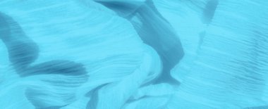 Mavi kumaş bulanıklığı, zengin dokusu ve yumuşak maddenin üzerine sarılmış ince iplikler. Kumaşın katmanları derinlik yaratır ve akış hissi yaratır.