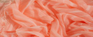 Yumuşak mercan kumaşından bulanık ışık, katıksız doku ve ince çizgiler. Katlar akışkan ve dalgalı bir görünüm yaratıyor, narin ve şeffaf materyali vurguluyor..