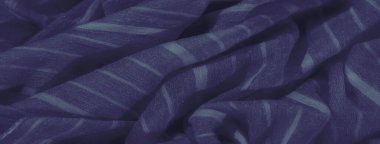 Dalgalı, yumuşak kıvrımlı, parlak bir yüzeyi olan zengin mavi kumaş bulanıklığı. Koyu mavi renk derinlik ve zarafet ekler, görsel olarak soyut bir doku yaratır.