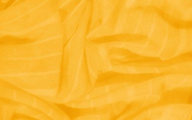 Altın sarısı kumaştan bir bulanıklık, narin yıpranmış iplikler ve nazik kıvrımlar ham, organik bir estetik oluşturuyor. Kumaşın canlı rengi sıcaklığı ve enerjiyi yayarak dokusuna derinlik katıyor..