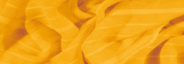 Yumuşak kıvrımları ve yumuşak kırışıklıkları olan dokulu sarı kumaş bulanıklığı. Kumaşın hassas iplikleri pürüzsüz yüzeye derinlik katar, ışığı yumuşak bir ışıltıyla yansıtır..