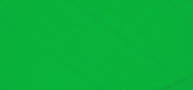 Dinamik kıvrımları ve yumuşak dokuları olan zengin yeşil bir kumaşın bulanıklığı. Kumaşın üzerindeki ince dalgalar ve desenler düz yüzeyini vurgulayarak görsel olarak çekici ve sakin bir sahne yaratıyor.