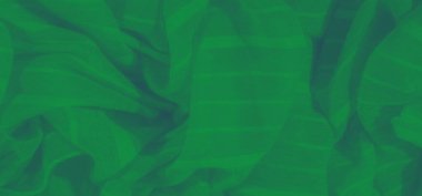 Yumuşak kıvrımları ve gölgeleri olan parlak yeşil kumaştan bulanık yumuşak ve huzurlu bir atmosfer yaratıyor. Malzemenin dokusu pürüzsüz ve pürüzsüz bir görsel akış sağlıyor..