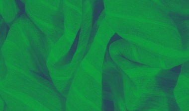 Yumuşak yeşil kumaştan ince kıvrımlar ve pürüzsüz bir dokuya sahip bulanık, narin maddeyi vurgulamak için nazikçe aydınlatılmış. Minimalist kompozisyon akışkanlığı ve yumuşaklığı vurgular.