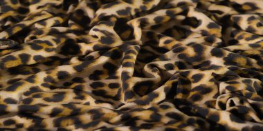 Bulanık, bu canlı leopar desenli kumaş sarı, siyah ve bej renkli gösteriler karmaşık kıvrımlar ve lüks bir doku, cesur ve dinamik bir moda sunuyor..