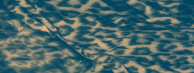 Yumuşak bej ve deniz mavisi desenli bulanık zarif kumaş. Pürüzsüz doku ve kıvrımlar, arka planlar, tekstil modelleri veya tasarım uygulamaları için mükemmel, kusursuz bir görsel efekt yaratır..