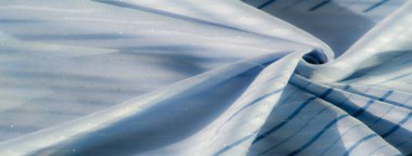 Açık mavi kumaş, şeffaf dalgalar ve ince çizgiler, ışığın ve gölgenin yumuşak etkileşimiyle vurgulanır, dinamik ve zarif bir görsel doku yaratır..