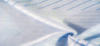 Bulanık, hafif açık mavi kumaş ince mavi dikey çizgiler ve ince parlak detaylar, pürüzsüz, dalgalı dokuyu ve nazik kırışıklıkları vurgulamak için güneş ışığını yakalıyor..