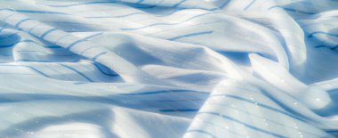 Yumuşak kıvrımları hafif ışıkla aydınlatılan bulanık mavi çizgili kumaş. Işıltılı ve ince dokular, arka plan ve tasarım için ideal bir ortam yaratıyor.