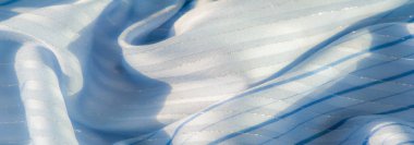 Işıldayan çizgileri ve yumuşak ışığı yansıtan nazik kıvrımları olan bulanık mavi kumaş. Tekstil lüks ve havadar bir havaya sahip. Bu da onu zarif arka planlar ve moda tasarımı için ideal kılıyor.