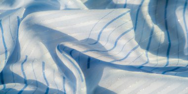 Işıldayan çizgileri ve yumuşak ışığı yansıtan nazik kıvrımları olan bulanık mavi kumaş. Tekstil lüks ve havadar bir havaya sahip. Bu da onu zarif arka planlar ve moda tasarımı için ideal kılıyor.