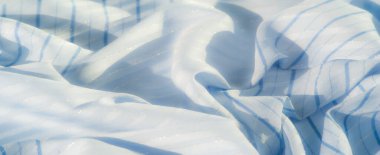 Yumuşak, açık mavi kumaş, ince parlak detaylar ve yatay çizgiler. Hassas kıvrımlar ve kalıplar sakin ve barışçıl bir görsel etki yaratır..