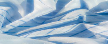 Yumuşak, açık mavi kumaş, ince parlak detaylar ve yatay çizgiler. Hassas kıvrımlar ve kalıplar sakin ve barışçıl bir görsel etki yaratır..