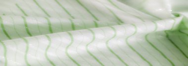 Pürüzsüz yeşil tonlarda ve parlak yatay çizgilerle bu kumaş barışçıl ve soyut bir tasarım yaratıyor. Hafif yansımalar yumuşak kıvrımlara ve dokulara ince bir zarafet ekler.