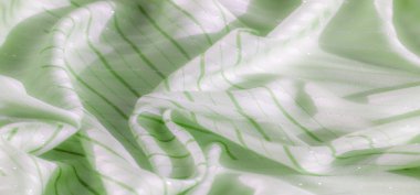 Çapraz çizgileri parıldayan buruşuk yeşil kumaş. Yumuşak doku ve parlak ışıkların birleşimi hareket ve lüks hissi yaratır..