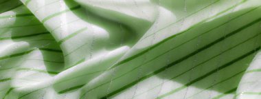 Parıldayan köşegen çizgileri olan bulanık yeşil kumaş. Yumuşak madde, hafif yansıtan ışık, zarif kıvrımlar oluşturur, zarif, havadar bir görsel oluşturur..