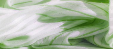 Açık yeşil kumaşın parlak, gümüş aksanlı ve ince dikey yeşil çizgili bulanık görüntüsü. Yumuşak dokusu ve narin desenleri yumuşak ve zarif bir görünüm yaratır.,