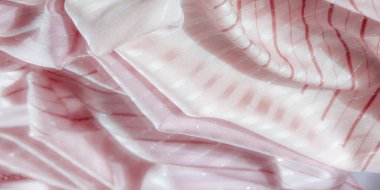 Yumuşak pembe kumaşlar, akışkan kırmızı çizgiler ve parlak gümüş aksanlar, incelikle katlanmış zarif şekiller, narin ve ışıltılı bir tekstil yaratıyor..