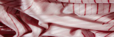 Kumaşın ince kırmızı çizgileri ve ışıldayan gümüş aksanları kendi içine katlanmış dalga benzeri bir etki yaratıyor. Kusursuz akış ve hassas detaylar materyallerin yumuşak dokusunu ve modern görünüşünü vurguluyor.
