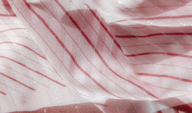 Zarif bir şekilde örtülmüş pembe kumaş, kırmızı, parıldayan dalgalı desenler. Yumuşak kıvrımlar ve parlak dokular ışık ve rengin akışkan ve sanatsal bir görüntüsünü oluşturur.