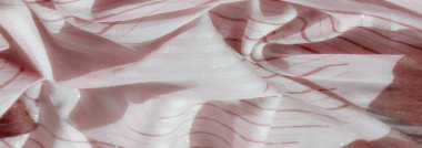 Zarif kırmızı çizgi desenleri ve parlak gümüş aksanlı pembe kumaşın bulanık görüntüsü. Kumaş karmaşık bir şekilde katlanmış, dinamik çizgiler ve dokular hafif parlak renklerle ortaya çıkıyor..