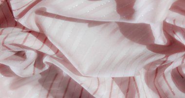 Yumuşak pembe kumaş, kırmızı çizgiler ve gümüş aksanlı bulanık bir görüntü. Kıvrımlı desenler, ışığı çeşitli kıvrımlarda yansıtan bir hareket hissi yaratıyor..