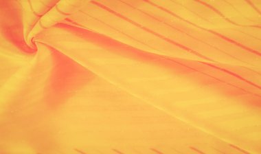 Çapraz çizgileri olan soyut sarı kumaş. Yumuşak kırmızı tonlara karışıyor. Çarpıcı ama pürüzsüz bir doku yaratıyor..