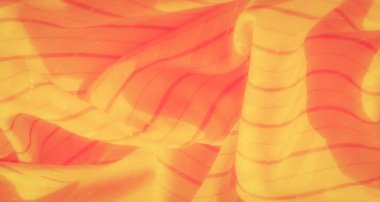 İnce parlak dokuları ve zarif kıvrımları olan sarı ve kırmızı çizgili bir kumaş. Yumuşak ve ılık renkler, tekstili narin ve büyüleyici gösteriyor..