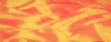 Bu görüntü, soluk kırmızı tonları ve geometrik çizgileri olan sarı kumaş görüntülerini yakına çeker. Doku yumuşak ve narin, neredeyse parlayan bir kalitede, sıcaklık ve parlaklık hissi katıyor..