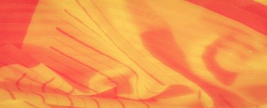 Bu görüntü, soluk kırmızı tonları ve geometrik çizgileri olan sarı kumaş görüntülerini yakına çeker. Doku yumuşak ve narin, neredeyse parlayan bir kalitede, sıcaklık ve parlaklık hissi katıyor..