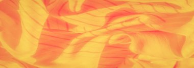 Dinamik çizgiler ve gölgelerin aktığı parlak sarı ve turuncu kumaşın bulanık görüntüsü. Yumuşak, pürüzsüz madde kıvrımları, sıcak ve parlak bir dokuyu yansıtır..