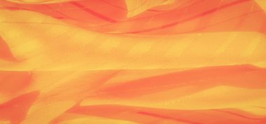 Bulanık sarı ve turuncu kumaş yumuşak kıvrımlarla örtülmüş. Çizgili yüzeyde ışık ve gölgeler oynuyor.