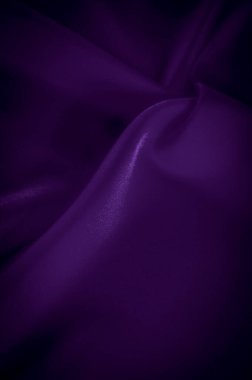 Katlanmış mor saten kumaşın bulanık görüntüsü, parlak dokuyu ve yumuşak örtüyü vurguluyor. Işık yansıması ışıltılı bir kalite ekler, bu da bunu harika bir görsel yapar.