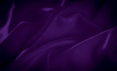 Hafif ışık yansımaları ve hassas kıvrımları olan mor saten kumaşın bulanık yakın çekimi yumuşak ve akışkan bir doku yaratıyor. Lüks tekstil tasarımları ve arka planlar için ideal.