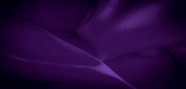 Hafif ışık yansımaları ve hassas kıvrımları olan mor saten kumaşın bulanık yakın çekimi yumuşak ve akışkan bir doku yaratıyor. Lüks tekstil tasarımları ve arka planlar için ideal.