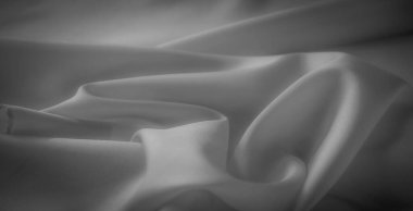 Bu gri pullu kumaşın bulanık detayları doğal ışıkla aydınlatılmış yumuşak kıvrımları ve kıvrımları ortaya çıkarır. Zarif gölgeler minimalist ve soyut kompozisyonu geliştirir..