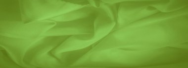 Görüntü, canlı yeşil kumaş yumuşak kıvrımları ve yumuşak dokusuyla dinamik bir bileşim oluşturuyor. Işığın kıvrımlar arasındaki etkileşimi kumaşın akışını ve kusursuz görünümünü arttırır..