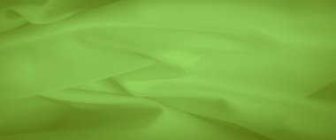 Parlak yeşil bir kumaşın bulanıklığı pürüzsüz kıvrımlar ve ince bir parlaklık sergiliyor. Materyalin yumuşak dokusu ve akışkan kıvrımları rahatlatıcı ve soyut bir görünüm yaratır. Tekstil tasarımları için ideal