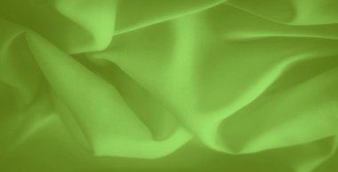 Görüntü, zarif kıvrımlı parlak yeşil kumaş çerçeveyi zarifçe kaplıyor. Düz yüzey, tasarım ve yaratıcı projeler için ideal olan tekstilin yumuşaklığını ve çok yönlülüğünü vurgular.