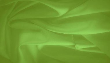 Yumuşak kıvrımlı, pürüzsüz, parlak yeşil kumaştan oluşan bulanık katmanlar yumuşak bir doku oluşturur. Canlı renk ve ince gölgeleme kumaşların akış görünümüne derinlik ekler.