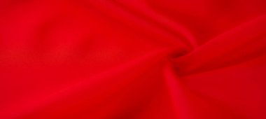 Sıvı kıvrımlı parlak kırmızı kumaş, ışığı yakalıyor ve yumuşak, lüks bir dokuyu ortaya çıkarıyor. Zengin renk ve dinamik kıvrımlar soyut, akışkan bir tasarım yaratır..