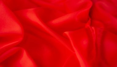 Görüntü, parlak kırmızı bir kumaş. Nazik ve kıvrımlı. Kalın kırmızı renk ve yumuşak kıvrımlar tasarım ve moda projeleri için mükemmel bir minimalist görünüm yaratıyor..