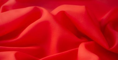 Canlı kırmızı kumaş bulanıklığı yumuşak, akışkan kıvrımlar yaratır, zarif bir kumaşla pürüzsüz ve kadife bir doku sergiler, arka plan veya tekstil tasarımları için idealdir.