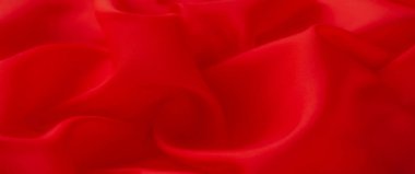 Yumuşak kıvrımlar ve yumuşak ipek dokularla karakterize edilen kırmızı kumaş yüzeyinin bulanıklığı. Zengin, canlı kırmızı renk kumaş tasarımı için göz alıcı bir görüntü yaratır..