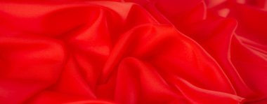 Canlı kırmızı kumaş bulanıklığı yumuşak kıvrımlar ve pürüzsüz doku gösteriyor. Lüks kumaşlar soyut arka planlar için zarif, şık ve dinamik bir görsel yaratıyor..